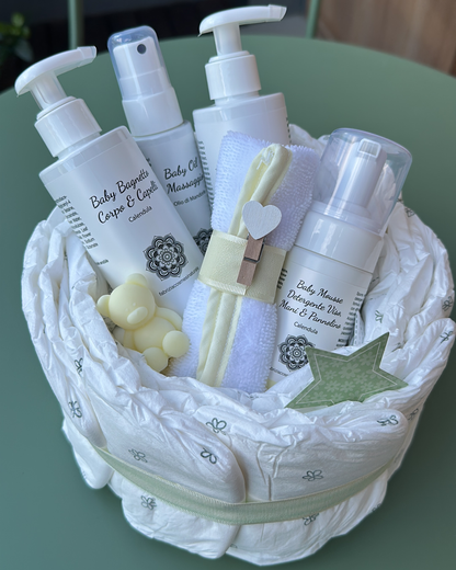 Torta Pannolini Fabrizia Cosmesi Naturale sul tavolo, con Baby Bagnetto, Baby Oil Massaggio, Baby Mousse e Manopola Baby: esempio di composizione, i cosmetici non sono compresi
